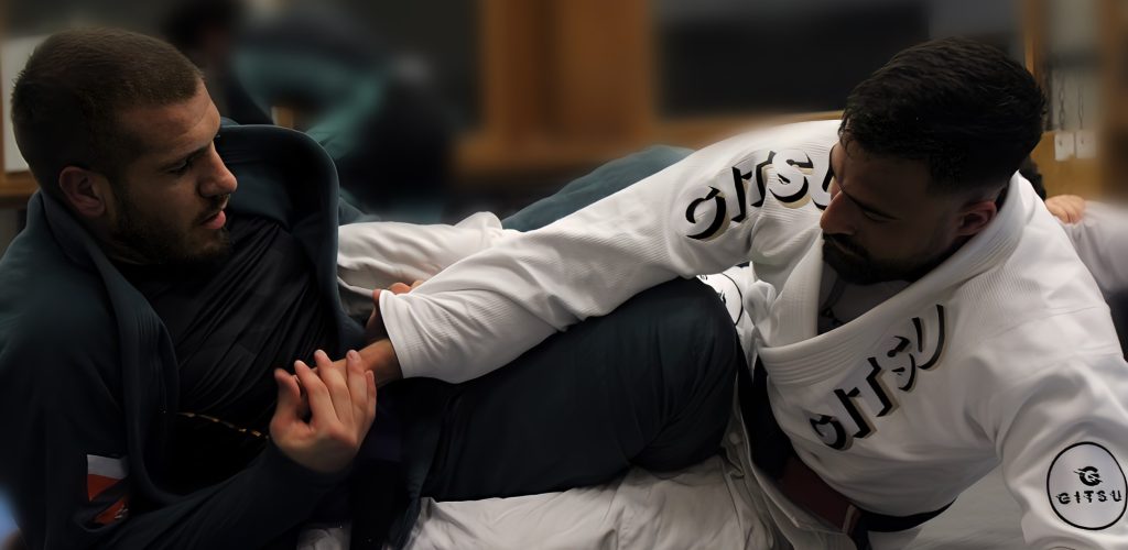 Sparring de Jiu-Jitsu Coach Abderrahman enseignant les techniques de Jiu-Jitsu brésilien à un apprenti lors d’un entraînement pratique, mettant en lumière l’art martial au sol.