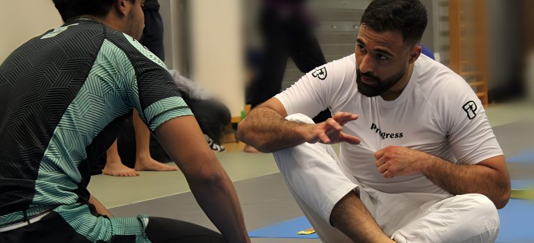 Session d(apprentissage du Jiu-JItsu Un coach de Jiu-Jitsu brésilien expliquant des techniques de combat à un élève attentif lors d’une session d’entraînement.